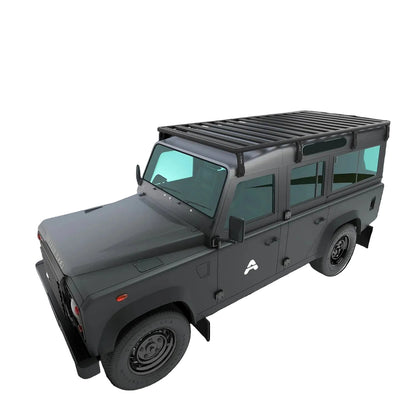 Das Bild zeigt einen Land Rover Defender 110 in Studioansicht aus der Dreiviertelperspektive von vorne links, leicht von oben. Auf dem Dach ist eine Airholder Dachplattform als großflächiger Dachträger montiert, die mit umlaufendem Rahmen und Querstreben eine stabile Ladefläche bildet. Die Konstruktion eignet sich für Overlanding- und Offroad-Zubehör wie Boxen, Bergeequipment oder Solarmodule und bietet viele flexible Befestigungspunkte auf dem Dach.

