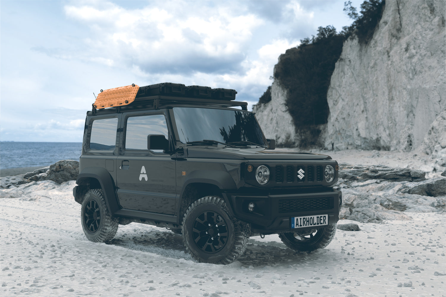 Suzuki Jimny Offroad am Küstenstrand mit Airholder Dachträger, beladen mit Sandblechen (Traction Boards) und Dachboxen/Transportkoffern für Overlanding.