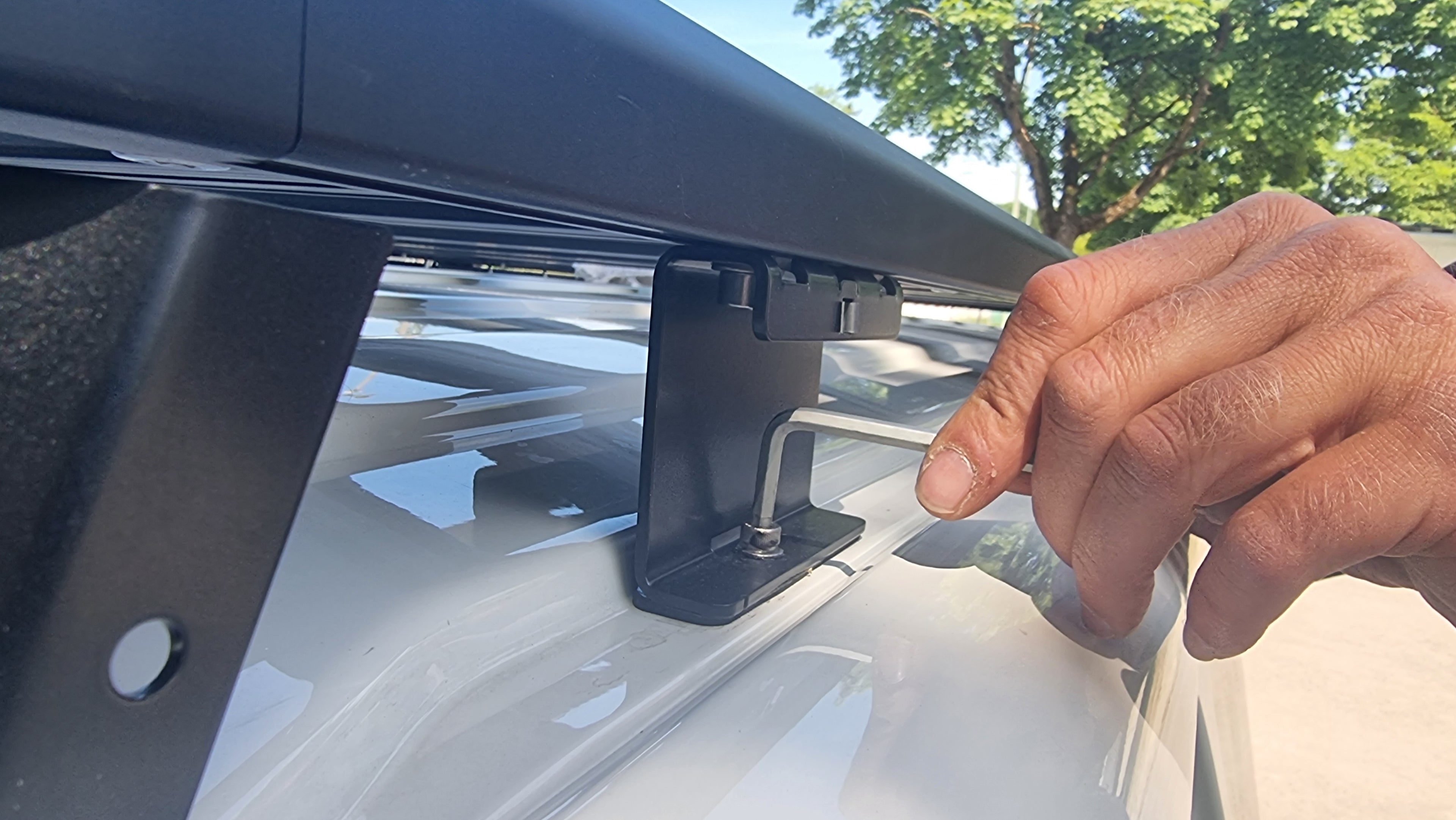 Nahaufnahme Befestigungsfuß des Airholder auf weißem Transporter, wird mit Inbusschlüssel angezogen.
